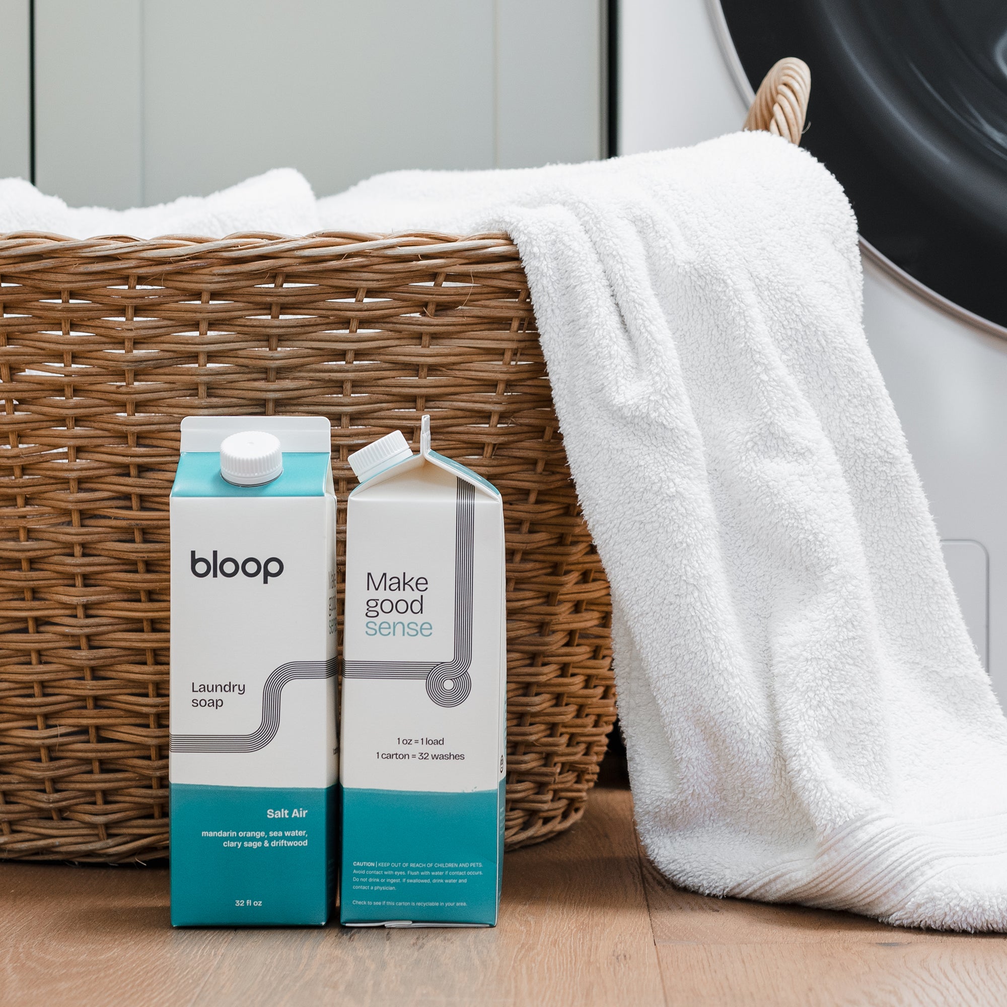 Two Cartons of Salt Air Natural Laundry Soap, front view and side view. 32 ounces. Plastic-free. Laundry basket behind product.