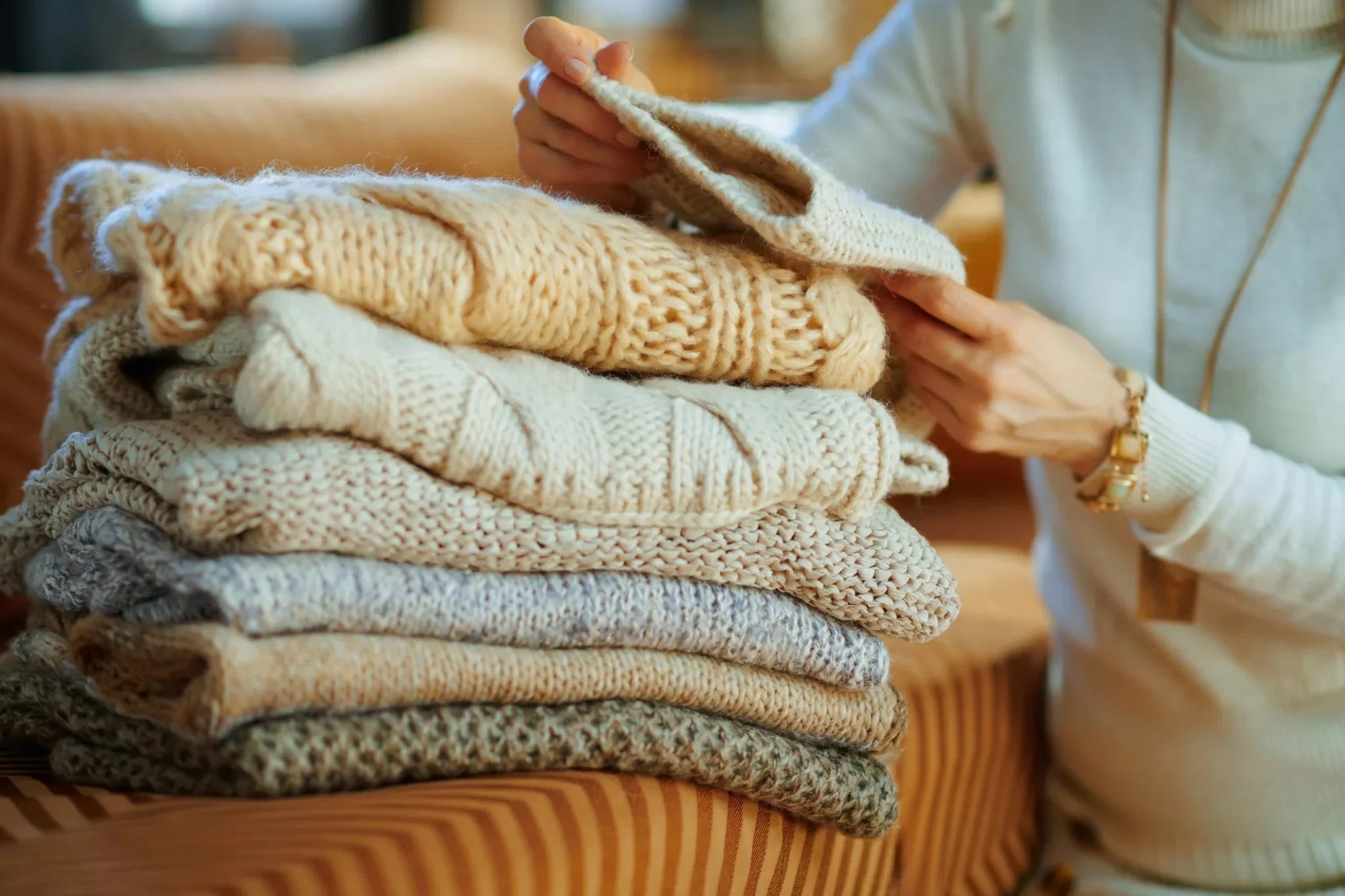 caring for delicate fabrics such as: silk, cashmere, athletic clothes, and heirlooms. Woman folds cashmere sweaters after laundry cycle. 