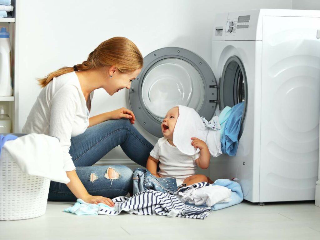 Photo young mom and baby in front of washing machine. 