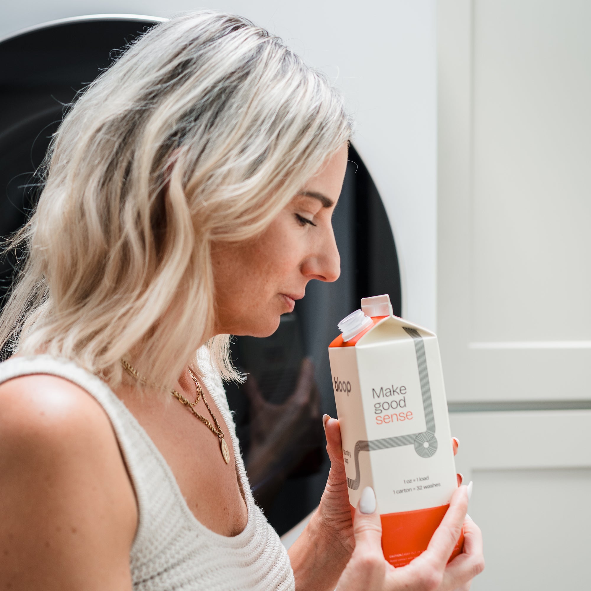 Women smelling Bloop Super Bloom Natural Laundry Soap in the laundry room.