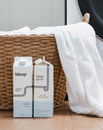 Two Cartons of Care Free Laundry Soap, front view and side view. 32 ounces. Plastic-free. Laundry basket behind product.